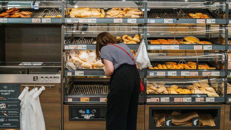 Woman in Aldi bakery section examining bread