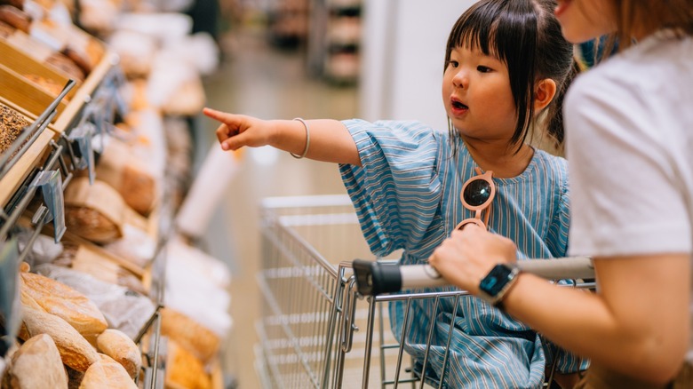 toddler points to treats in grocery store bakery