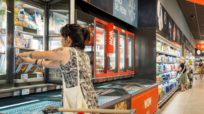 Woman reaching into frozen food case in an Italian Aldi store.