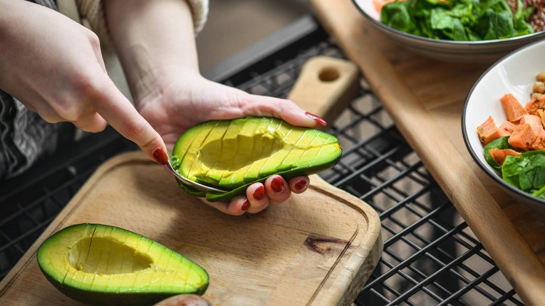 hands slice an avocado