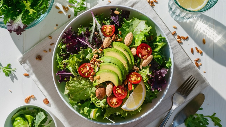 Vibrant mixed green salad topped with sliced avocado.