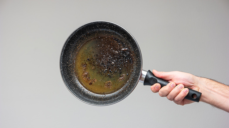 holding up pan filled with solidified leftover oil