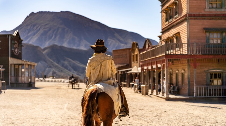 cowboy rides horse away from viewer