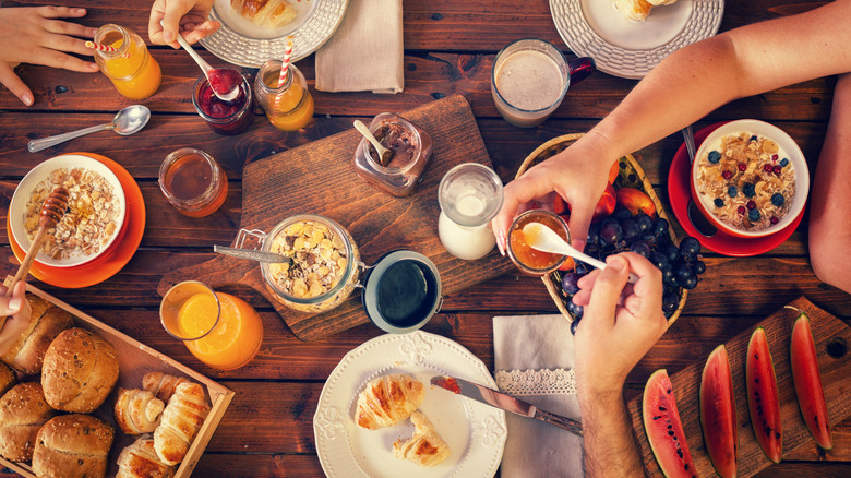 Overhead shot of breakfast spread on table with hands.