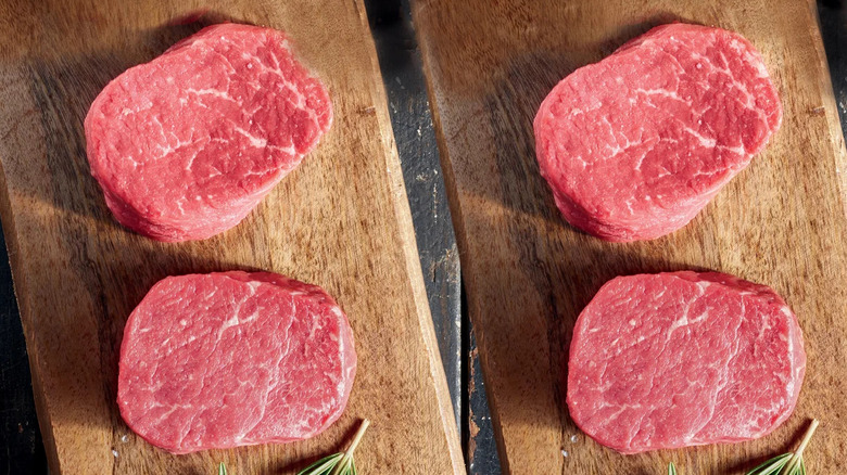 A top-down view of four Choice filet mignon steaks on wooden chopping boards, next to springs of rosemary