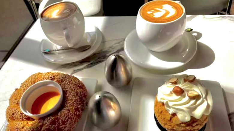 Table laid with two hot drinks, a Turkish bagel, and choux pastry