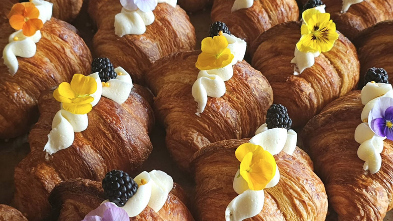 Rows of stuffed croissants garnished with edible flowers