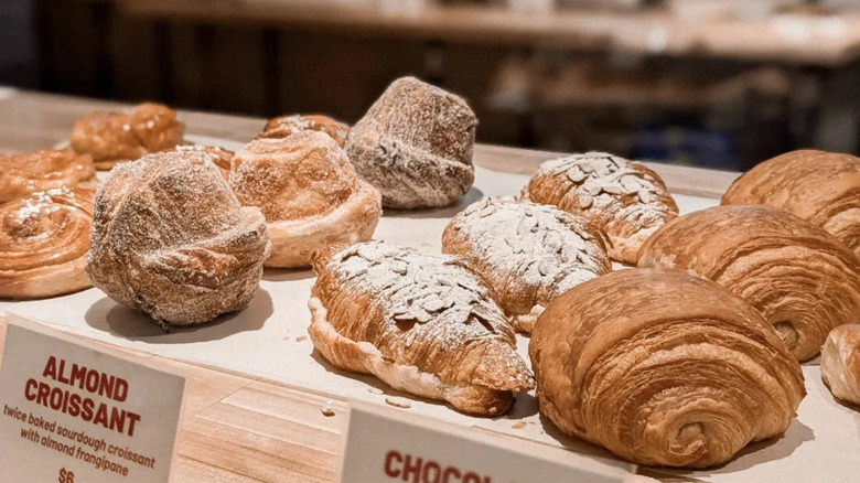 Wooden butcher block with lineup of croissants and laminated pastries