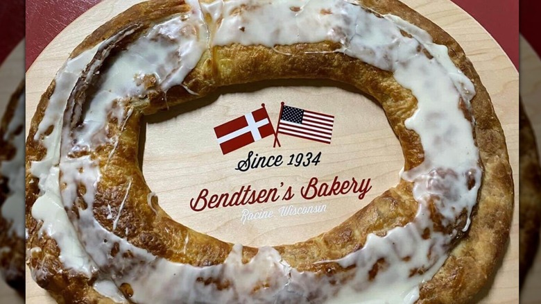 A delicious local favorite almond Danish Kringle with tray on burl surface.