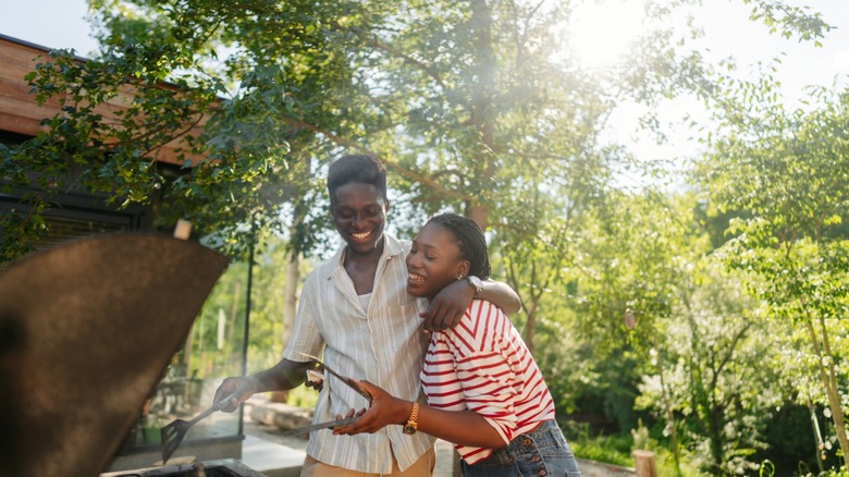 couple works the grill together at a barbecue