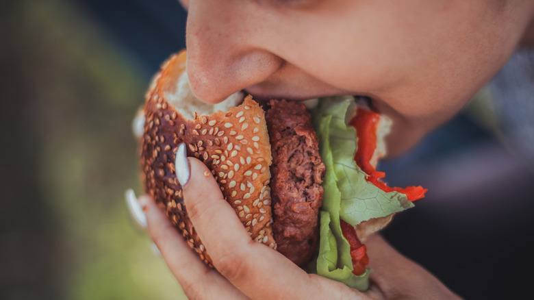 A woman taking a bite out of a burger