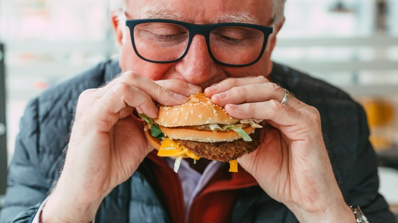 man eats burger with two hands