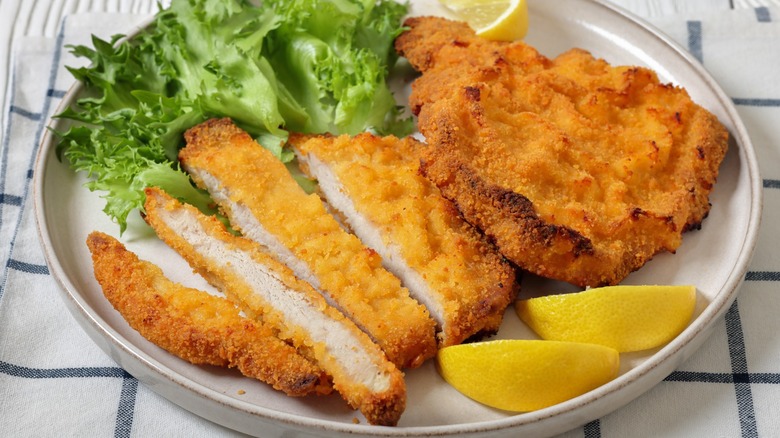 breaded pork milanese with lemon on white plate