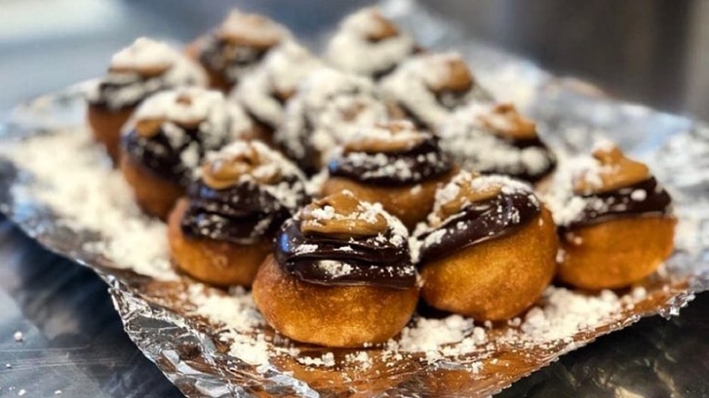 Pile of mini donuts with chocolate and icing sugar
