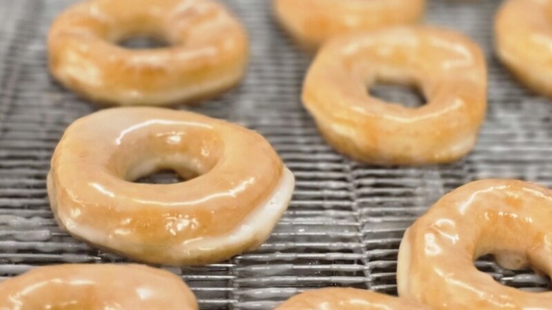 Lineup of freshly glazed donuts on a conveyor belt