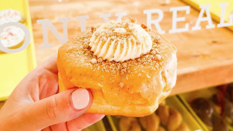 Hand holding a filled donut topped with meringue