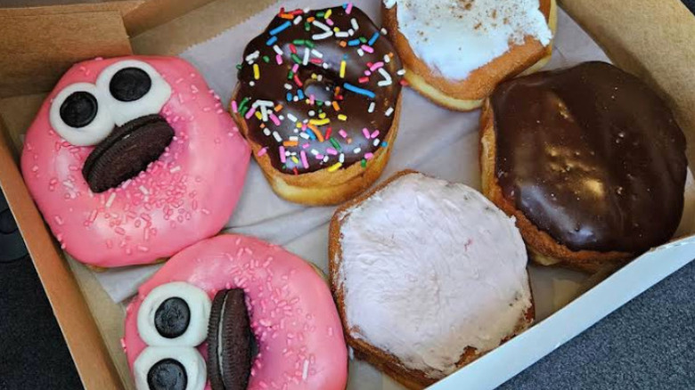 Box of six donuts, two pink, one sprinkle, one chocolate, and two with white frosting