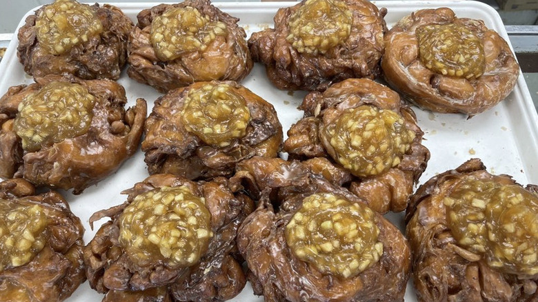 Freshly glazed large apple fritters on baking sheet