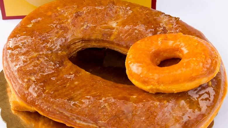 Gigantic glazed donut with regular sized glazed donut on top