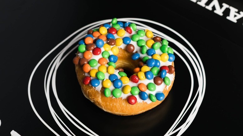 Donut decorated with mini M&Ms on black background