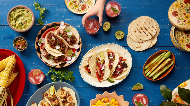 various Mexican dishes and drinks laid out on a blue table