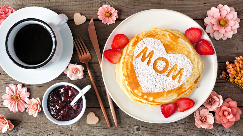 Mother's Day breakfast spread with pancakes topped with powdered sugar and "MOM" stenciled in