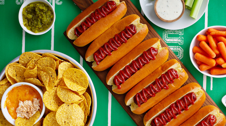 game day snacks and hot dogs arranged on a green background