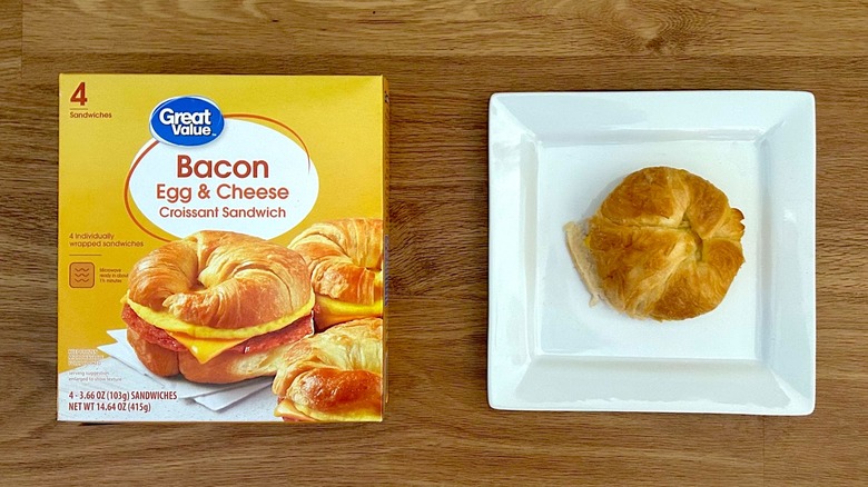 Package and cooked Great Value Croissant Sandwiches Bacon, Egg, & Cheese on square white plate