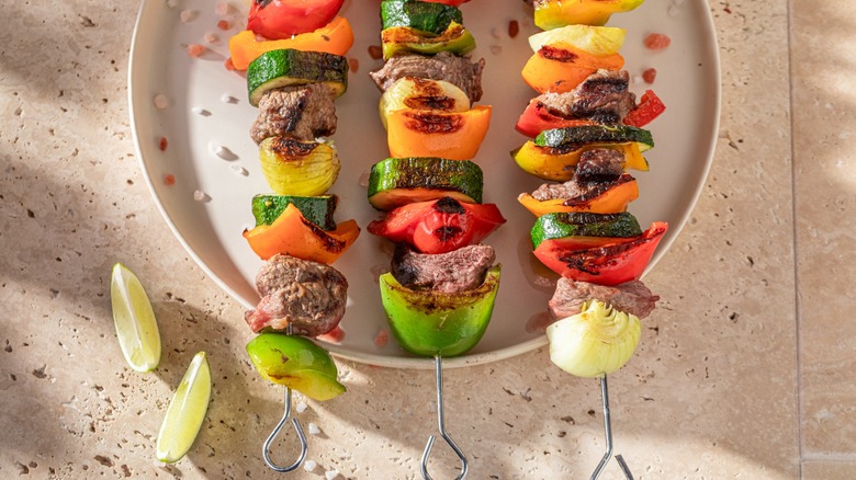 kebabs on metal skewers atop platter