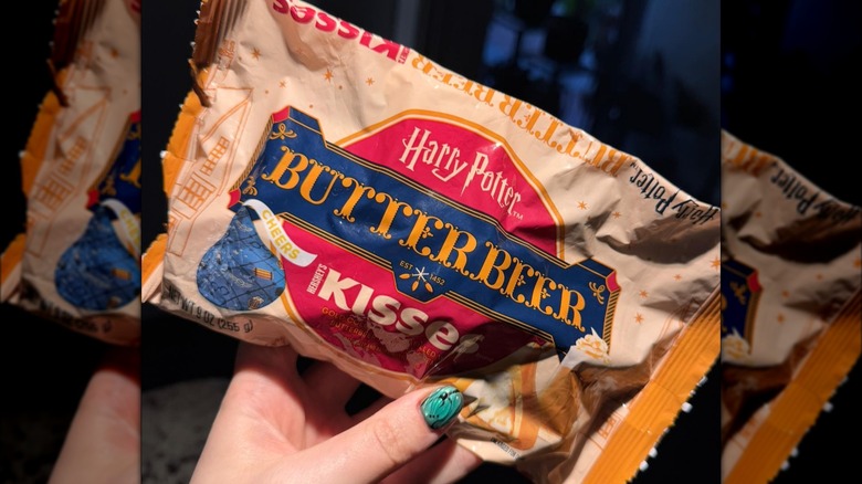 a hand holds a bag of hershey's butterbeer kisses