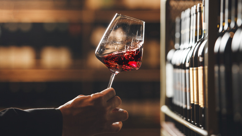 Someone swirling a glass of red wine in the sunlight