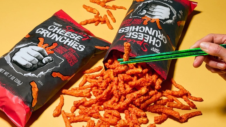 bags of spicy cheese crunchies spilled and held by chopsticks