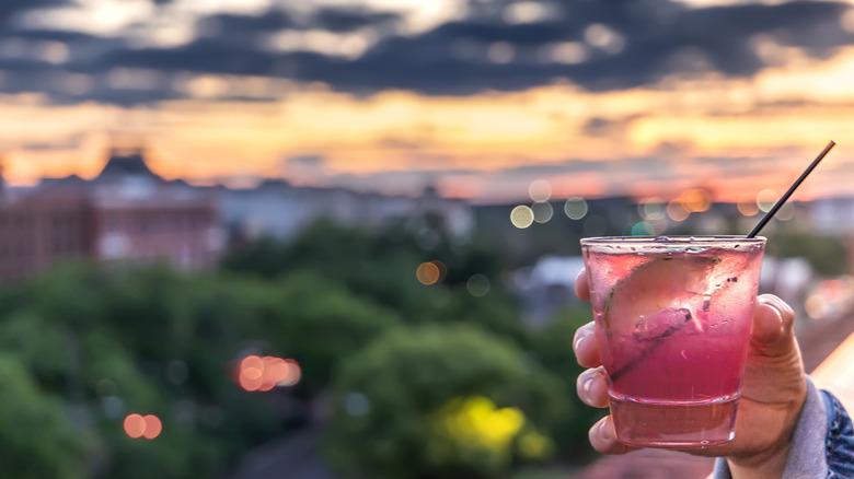 Someone holding a pink cocktail in a rooftop bar
