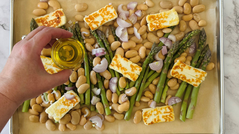 hand holding oil over sheet pan