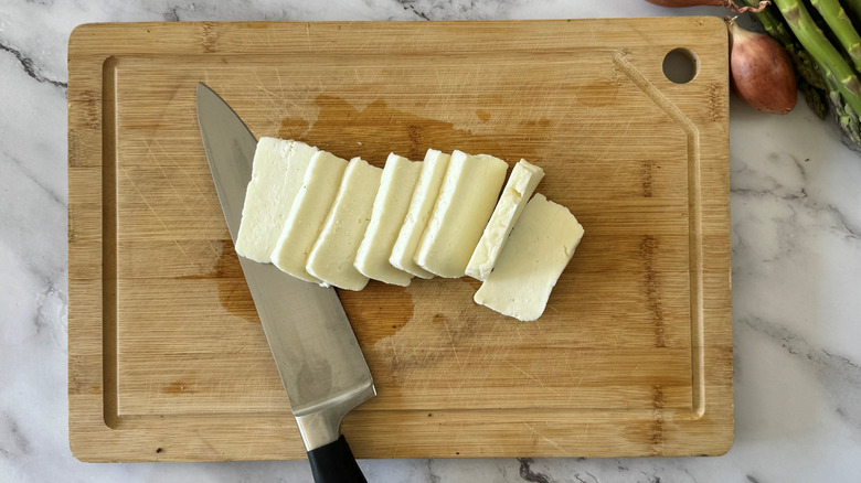 Halloumi cheese cut into rectangles next to knife