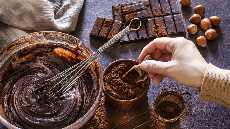 Mixing chocolate batter with baking chocolate and cocoa powder on the side