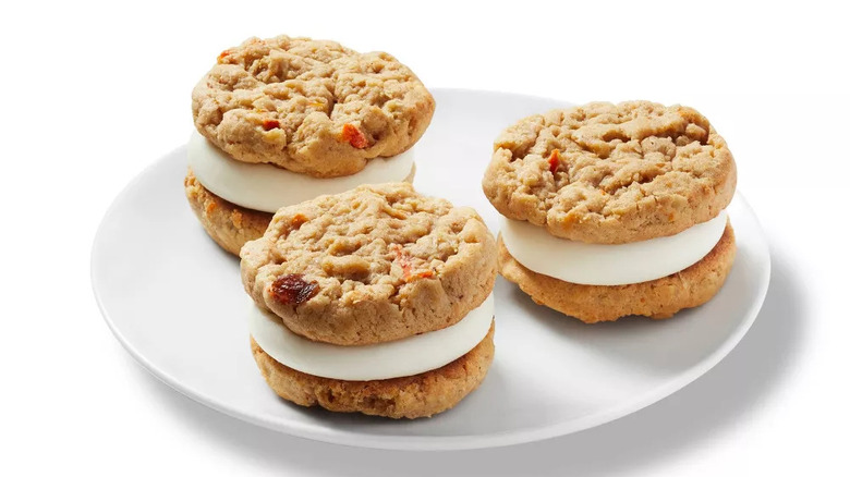 Three carrot cake sandwich cookies on a white plate