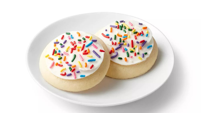 Two white frosted sprinkle sugar cookies on white plate