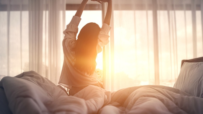 woman wakes up in the morning with sunrise