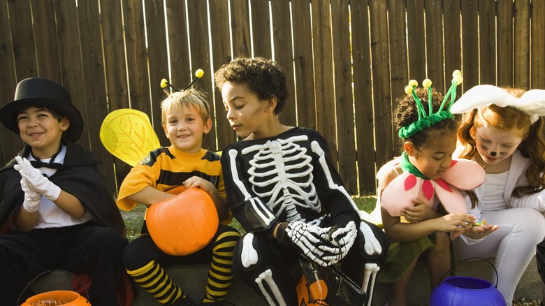 kids in halloween costumes exchange candy