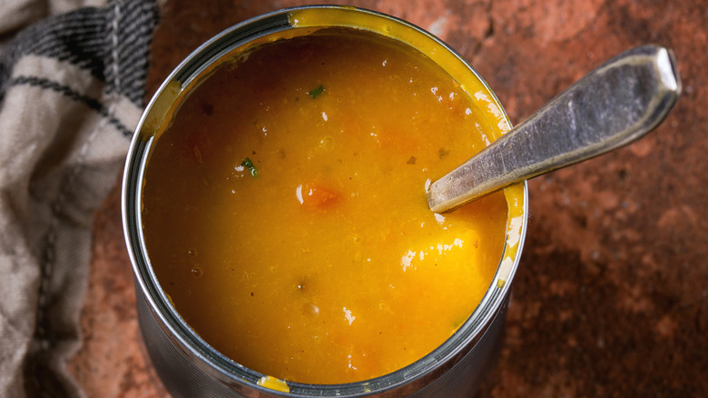 Tin can of carrot soup with spoon in it