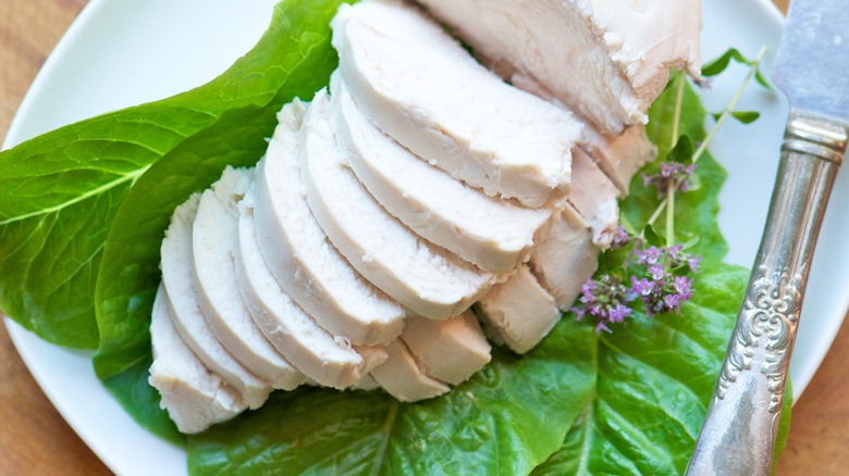 delicate poached chicken breast slices on lettuce leaf