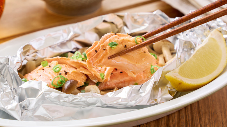 Chopsticks holding a piece of steamed salmon