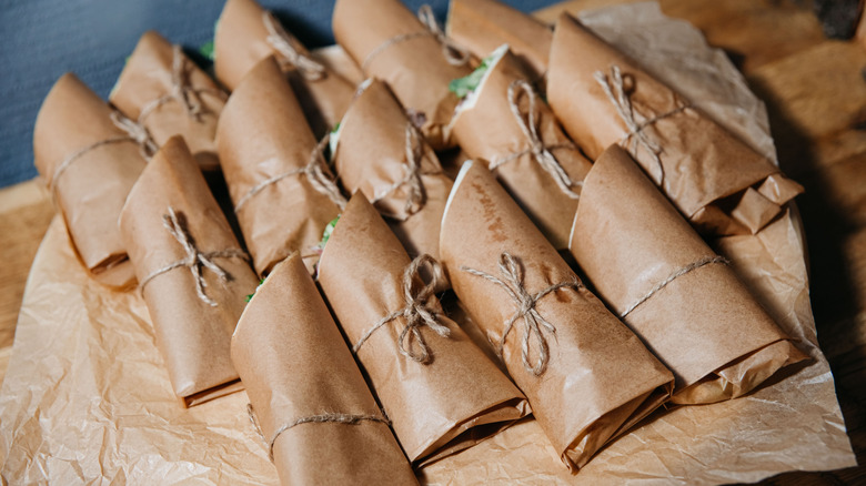 Several sandwiches wrapped in brown paper with twine tied around their centers