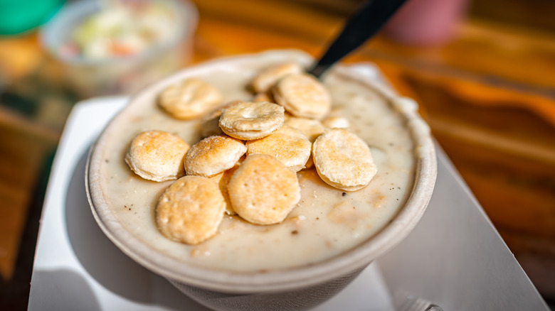 Bowl of clam chowder topped with handful of oyster crackers