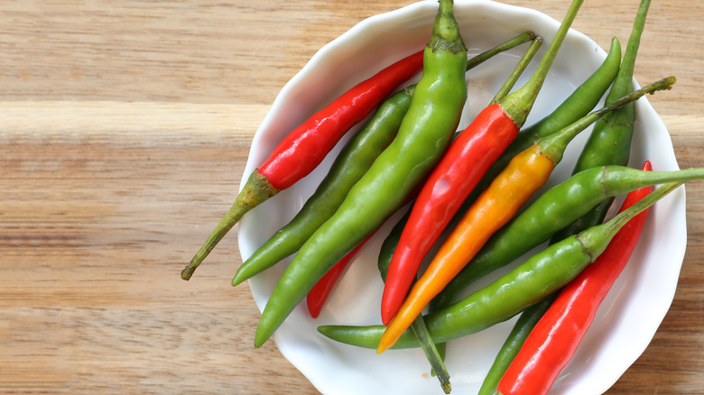 Spicy red and green chili peppers on wooden table