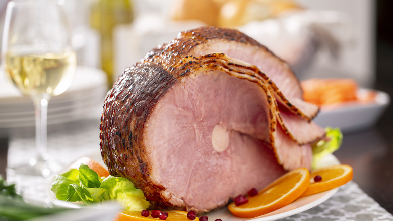 spiral sliced ham on a table with a glass of white wine blurred in the background