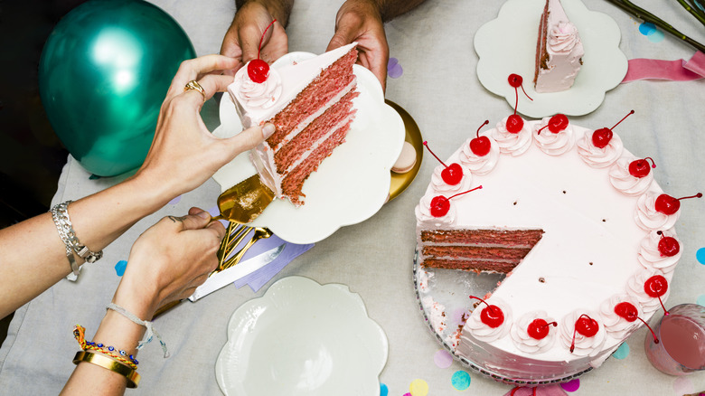 Slicing and serving a pink, layered cherry cake.