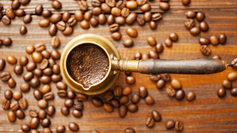 Turkish coffee holder and beans on a wooden surface