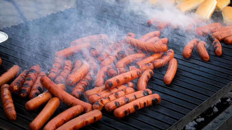 A shot of a large amount of hot dogs cooking on a grill